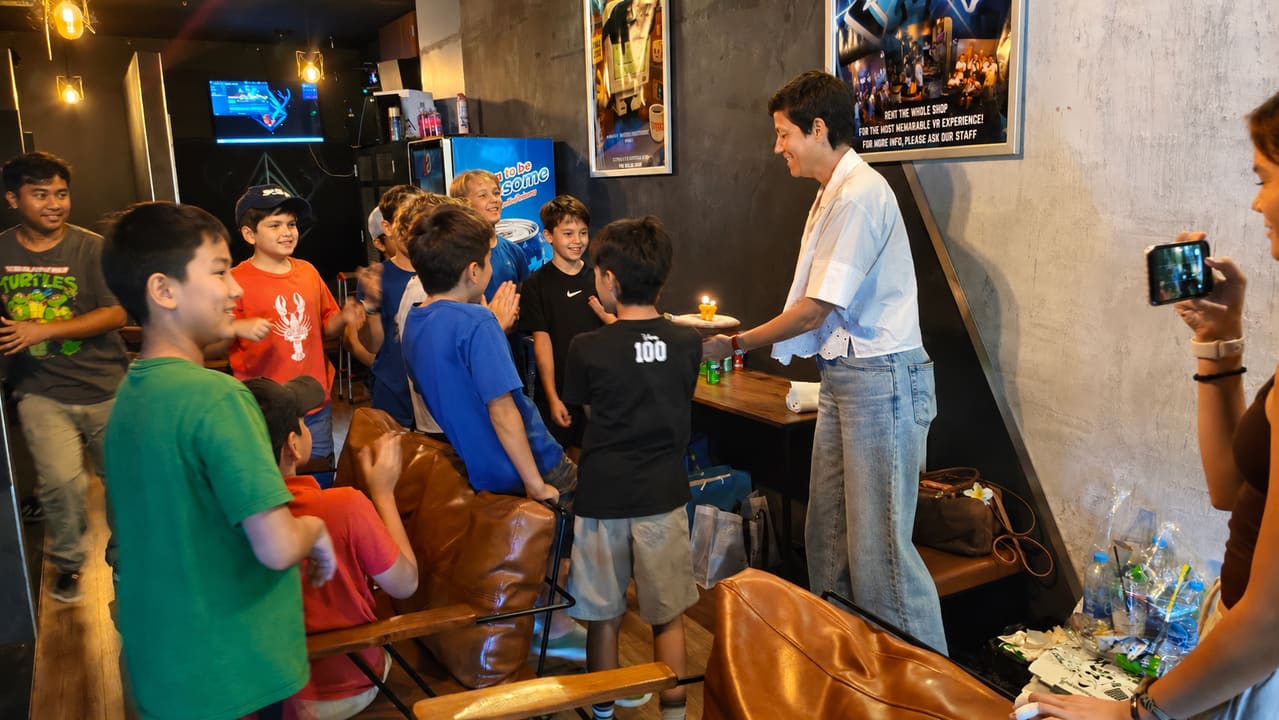 Kids gathered around a birthday cake with candles at Total VR