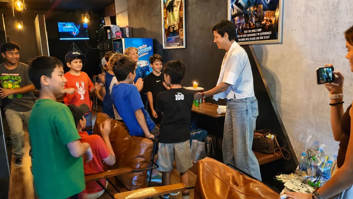 Kids gathered around a birthday cake with candles at Total VR